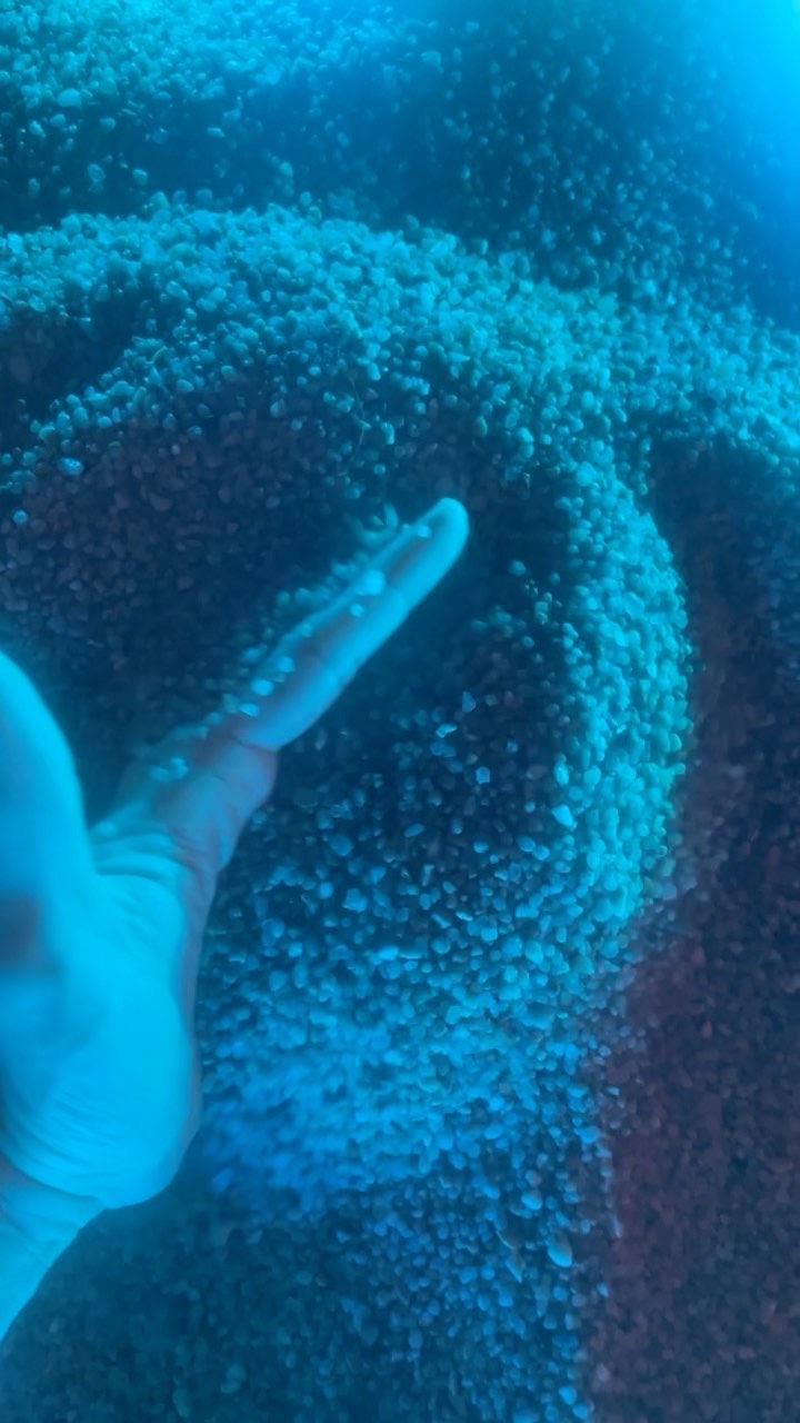 Mano che sfiora granuli di sale sotto luce blu